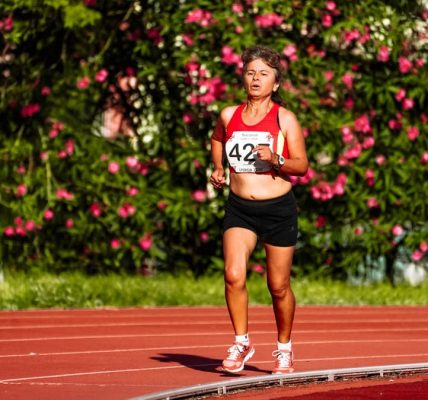 Middle aged female athlete in sportswear running during track and field competition while looking forward